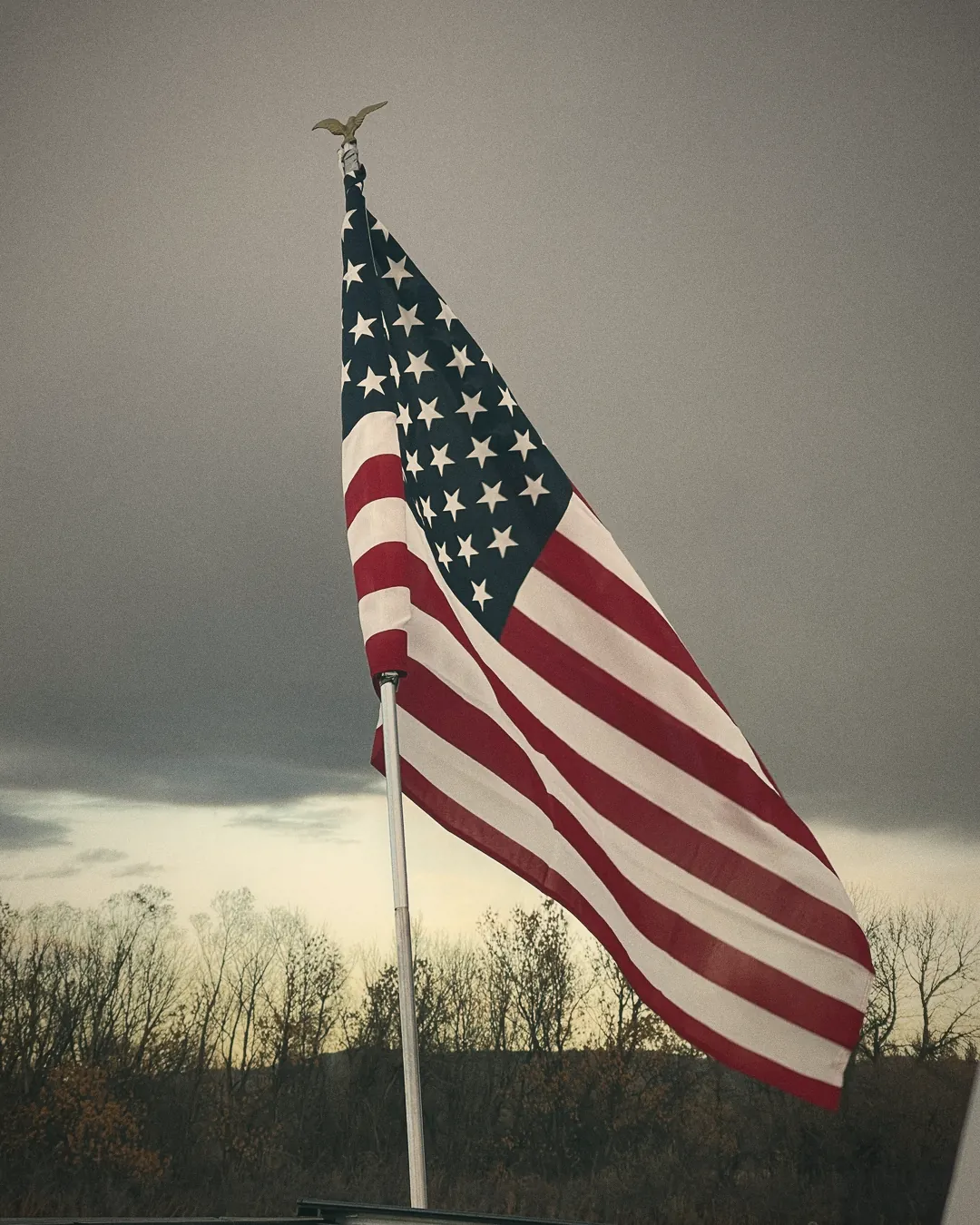 An American flag against a grey sky
