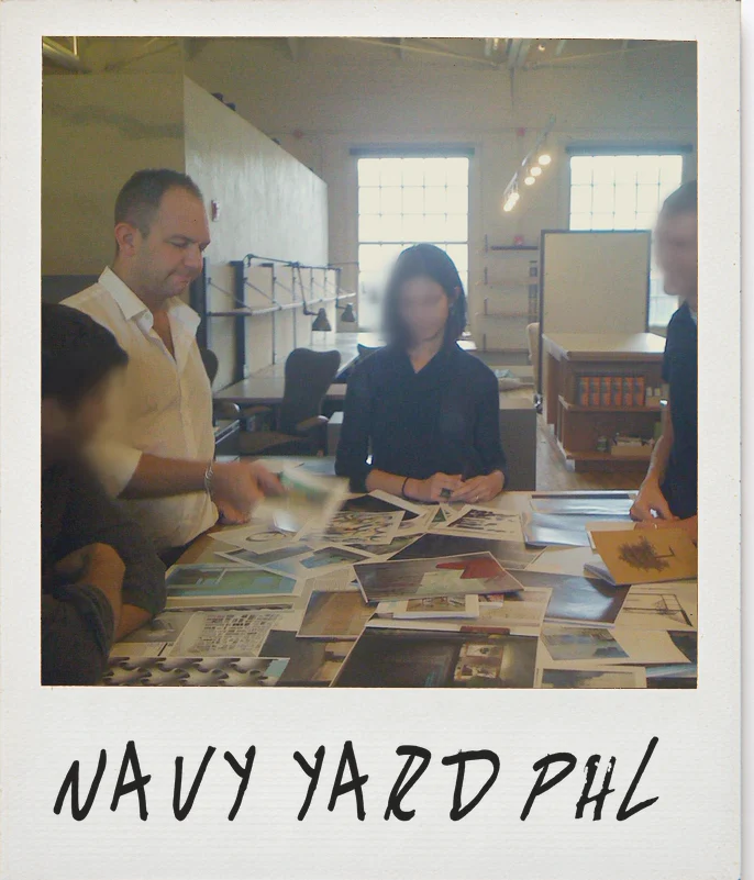 Photo, URBN&rsquo;s design studio at the Navy Yard, Philadelphia: James with his team around a table covered in prints, their faces softly blurred