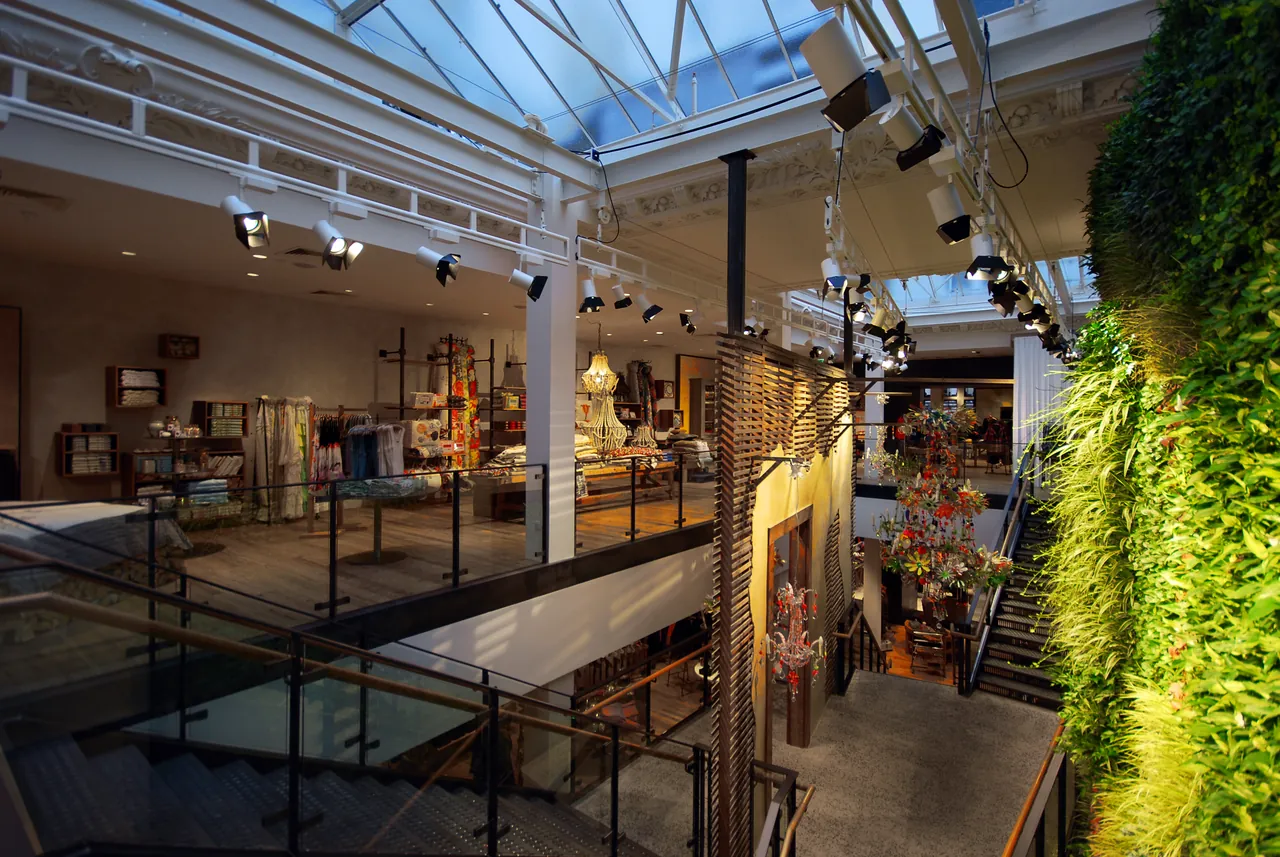 Anthropologie, Regent Street, London: the skylit hall inside the old building, a living wall of plants beside the stair down to the lower floor